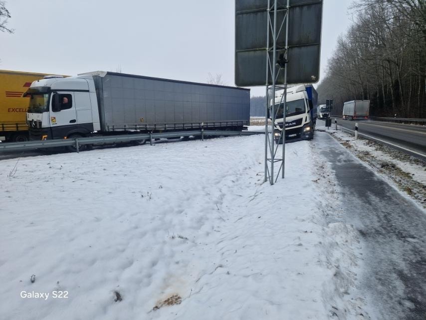 37c99e1f-d888-4672-b677-57d5b6a1e8dd – LKW Help 24 Na placu serwisowym znajduje się naczepa chłodnia podłączona do zasilania, gotowa do transportu towarów w odpowiednich warunkach temperaturowych. W tle widoczne są inne pojazdy, a na naczepie mogą być włączone światła pozycyjne dla zwiększenia widoczności.