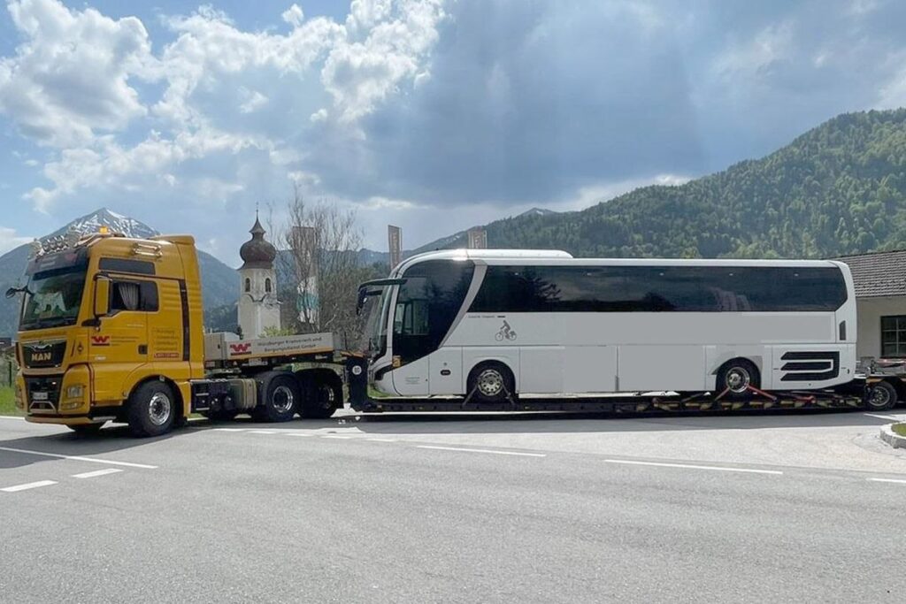 Reisebus auf Tieflader durch Bergregion transportiert – LKW Help 24