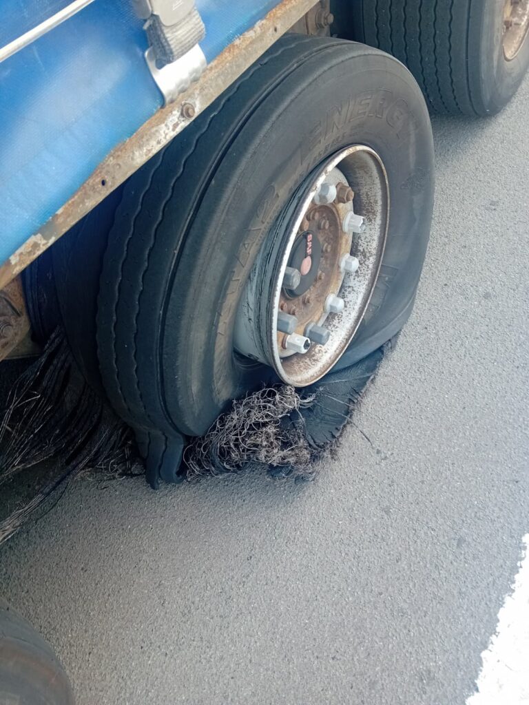 Destroyed truck tyre with exposed steel casing after a blowout