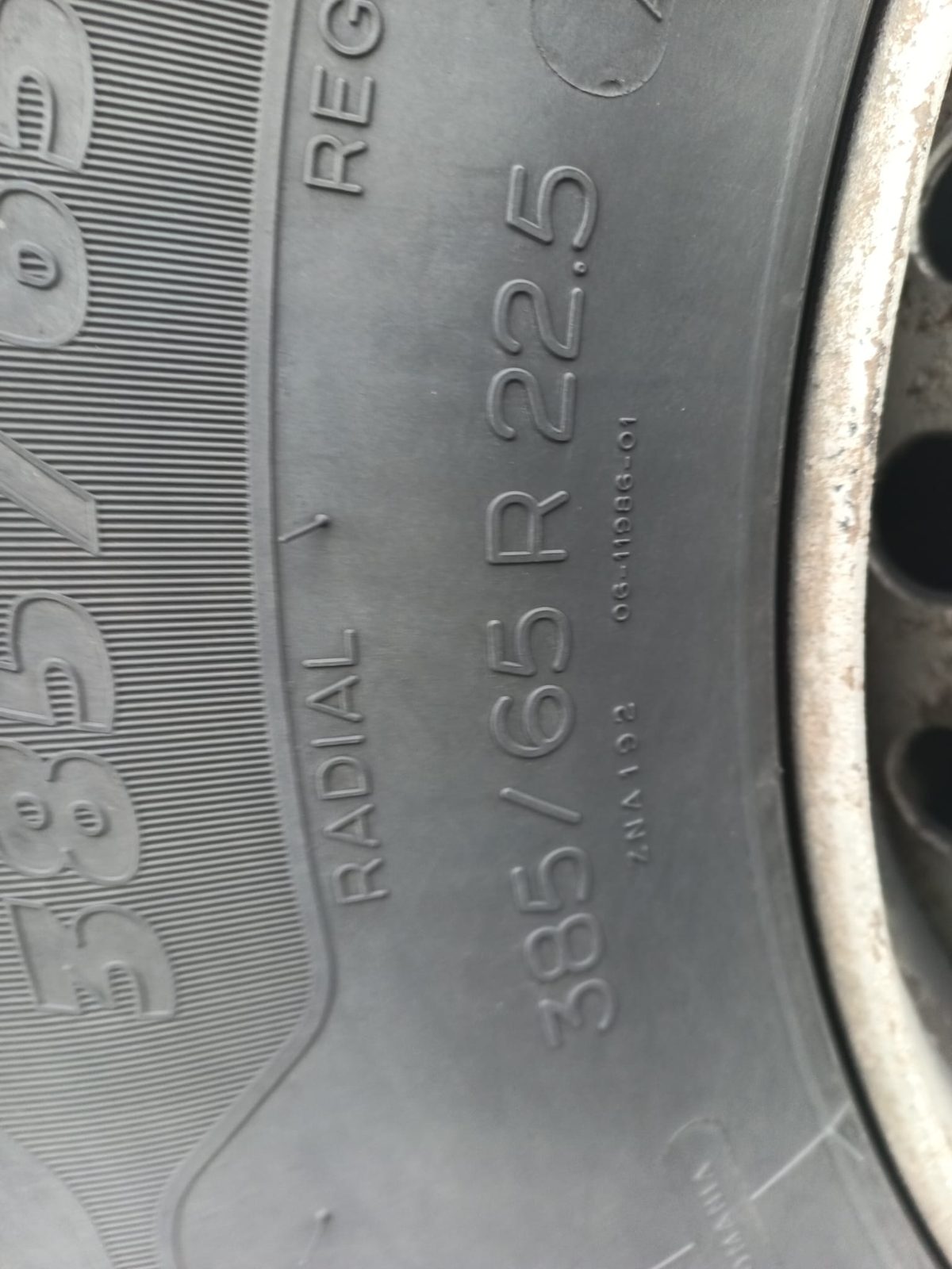 Serwis opon TIR: boczna ścianka opony 385/65 R22.5 i stalowa felga z lekką korozją powierzchniową